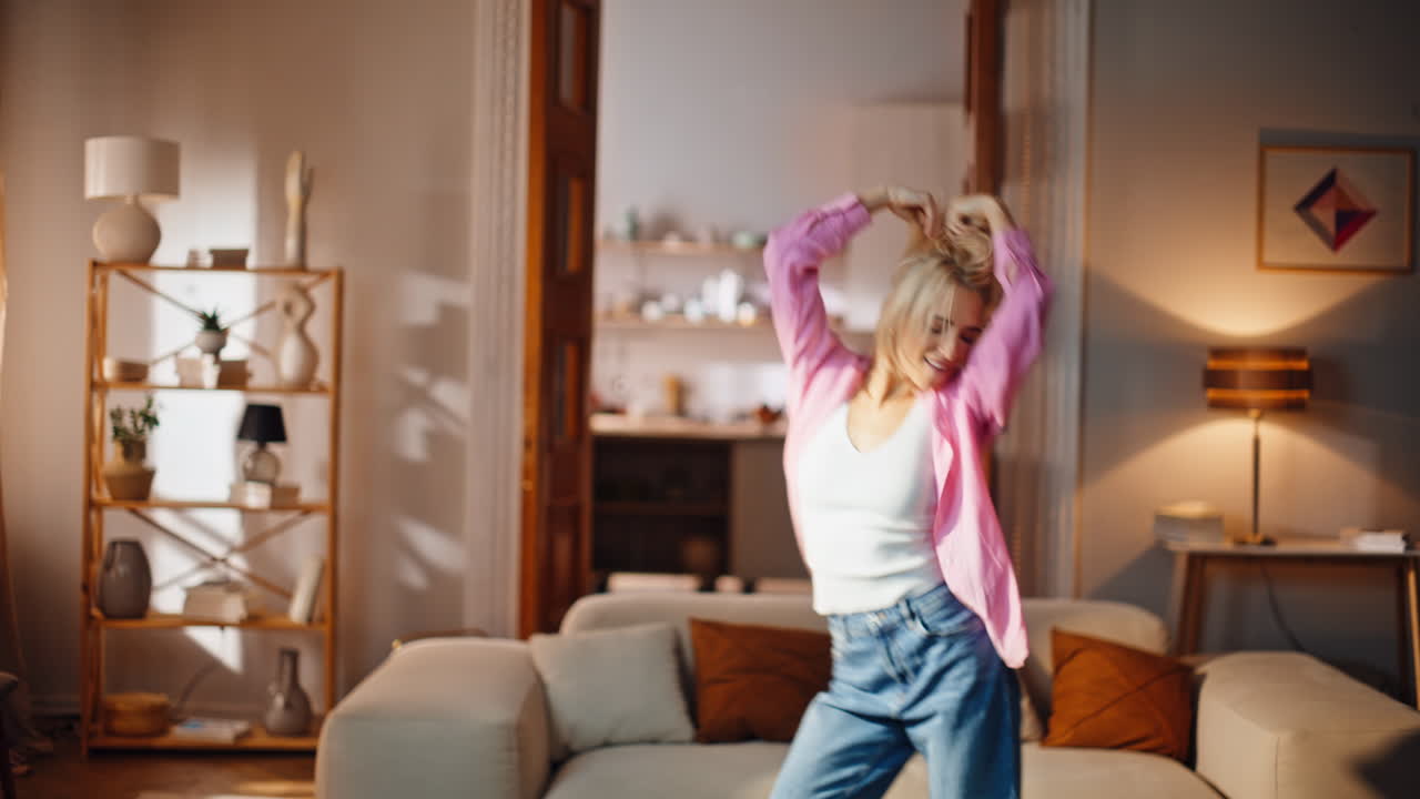 Lively woman dancing music feeling freedom in bright living room. Excited girl