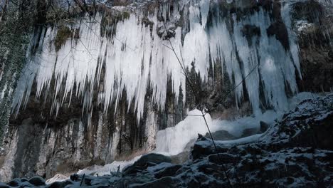 Sharp-icicles-hanging-on-a-stone-wall-mountain-of-Austria