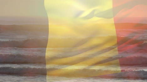 composición digital de ondear la bandera belga contra la vista de la playa y las olas del mar