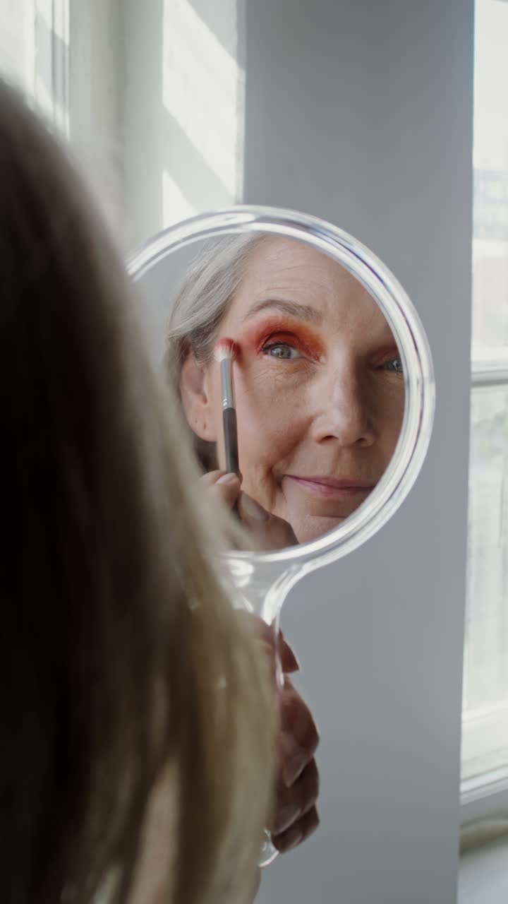 Woman applying eye makeup in a mirror