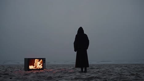 person on beach at night with burning tv