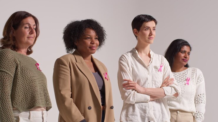 Studio Portrait Of Multi-Racial Group Of Women Of Different Ages Wearing Pink Breast Cancer Awareness Ribbons