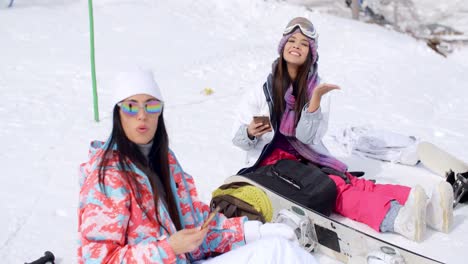 Dos-Mujeres-Atractivas-Practicantes-De-Snowboard-Relajándose