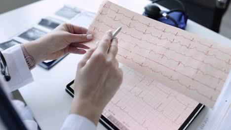 medical professional analyzing ecg results on paper and tablet