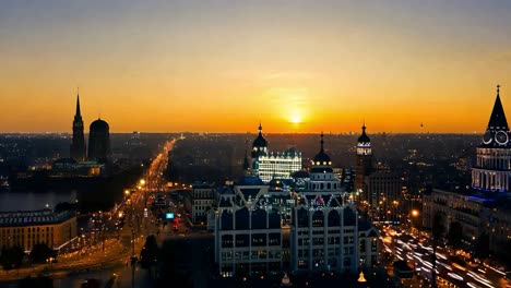 the sun sets behind a modern city skyline, casting an orange glow on the buildings and streets below