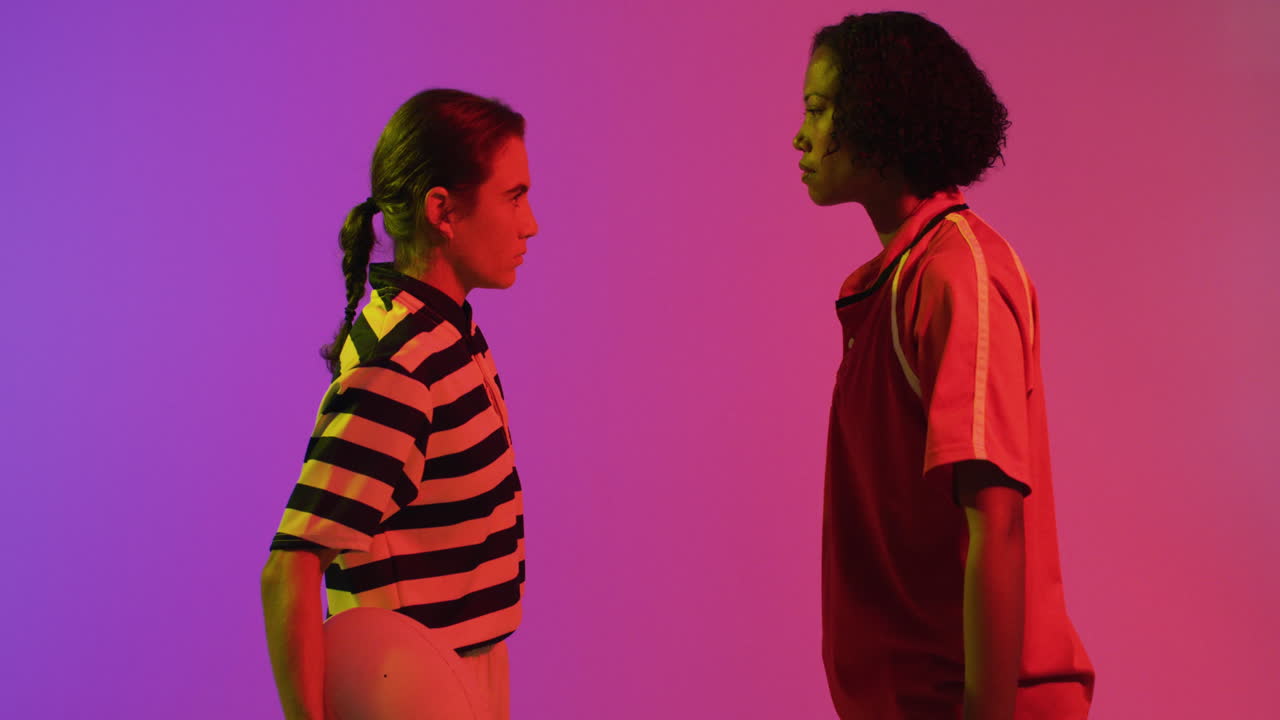 diversas jugadoras de rugby con pelota de rugby sobre iluminación rosa neón