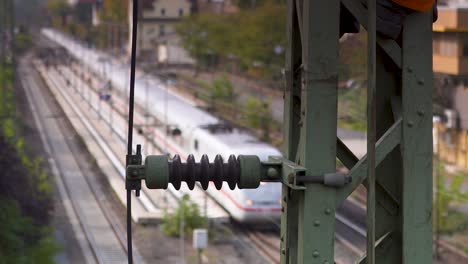 train approaching on tracks viewed through blurred industrial equipment at dusk, evoking a sense of transit and movement