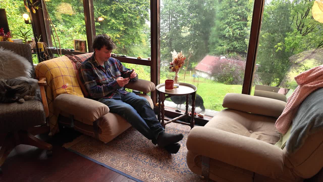 Man using smartphone sitting in cabin surrounded by nature