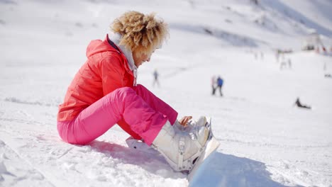 Skier-putting-on-her-snowboard