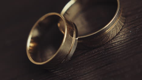 Pair-of-elegant-gold-wedding-rings-on-black-wooden-surface