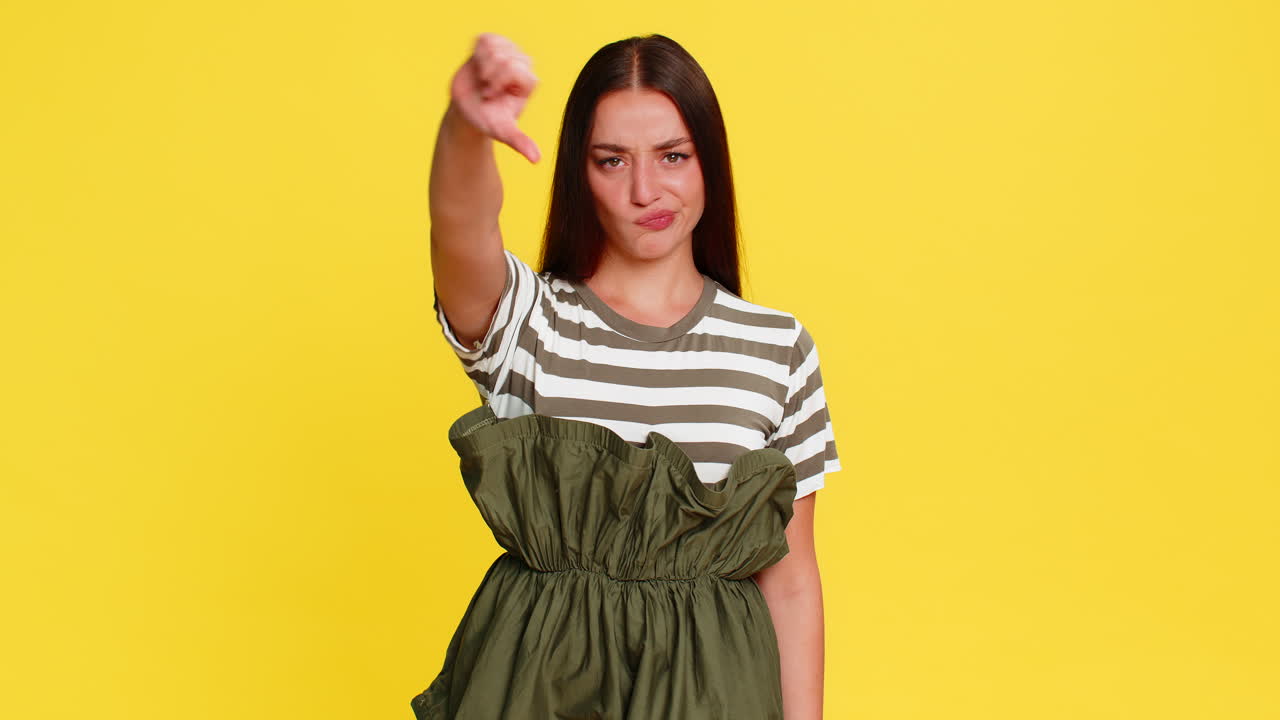 Woman showing thumbs down serious disappointed face expressing dislike rejection negative emotion