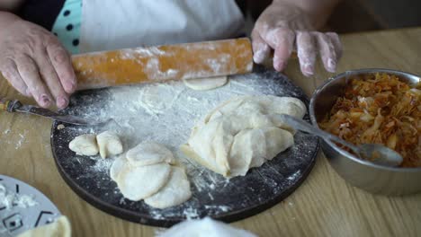 senior woman hands rolling pieces of dough with rolling pin