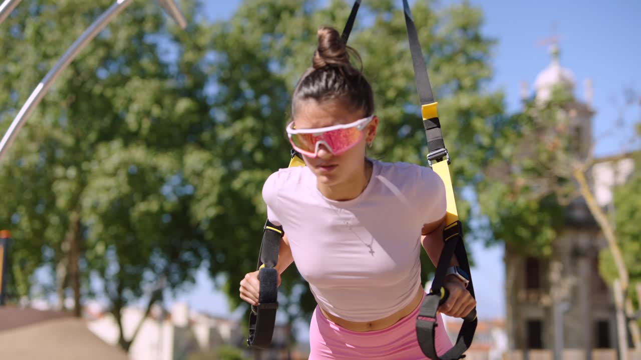 Woman doing TRX exercises in a park