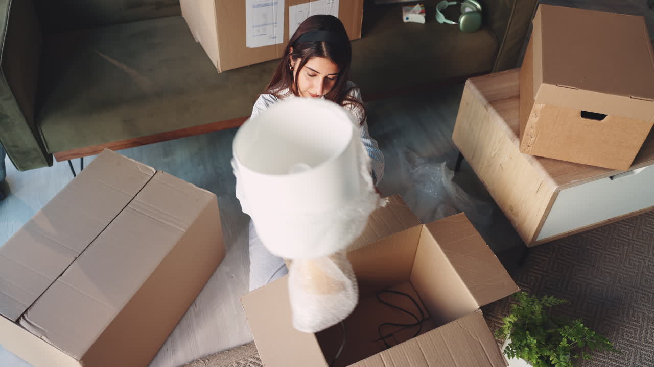 Woman unpacking lamp from moving box