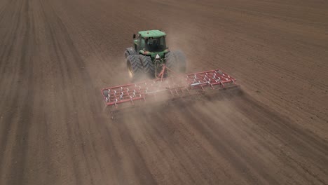 Green-tractor-pulls-tine-harrow-during-agriculture-seeding-in-field