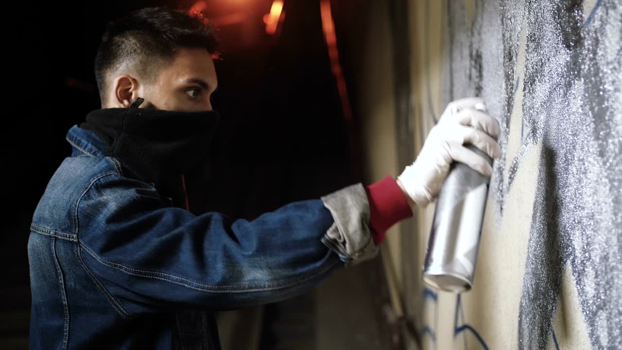 Graffitaro che dipinge sul muro della metropolitana