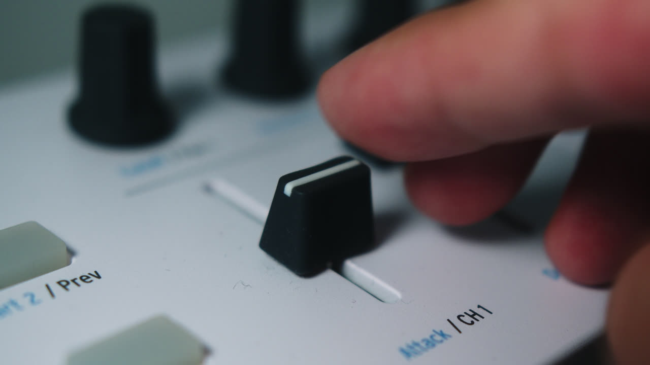 Amazing super close-up slow motion shot of a musician moving the volume fade of a keyboard with his finger while playing music in his room.