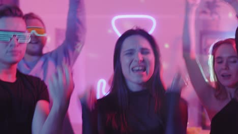 group of friends dancing at a party with neon lights decoration