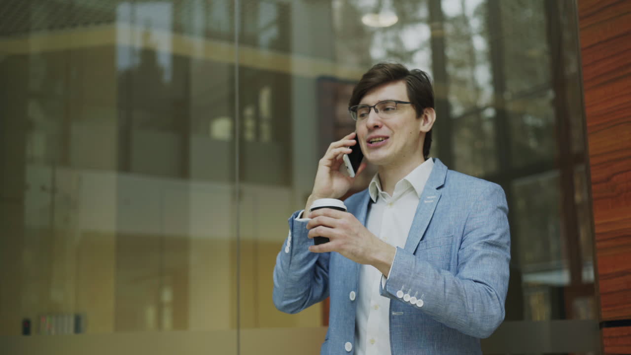 Businessman having a phone call while drinking coffee outside