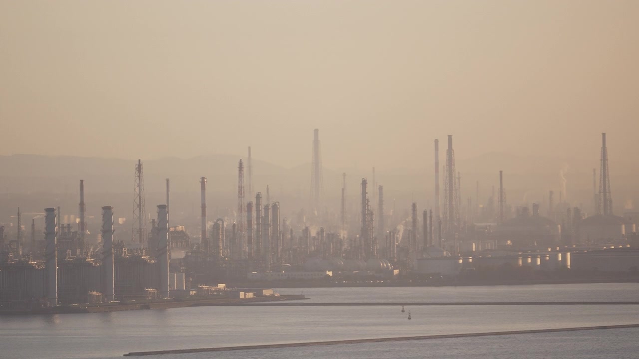 Wide view of industrial refinery towers in hazy atmosphere.