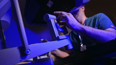 professional surgeon sitting and operating robotic medical equipment. doctor looks at special device and moves the handles. low angle view.