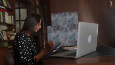 mujer estudiando en un escritorio con una computadora portátil y un cuaderno
