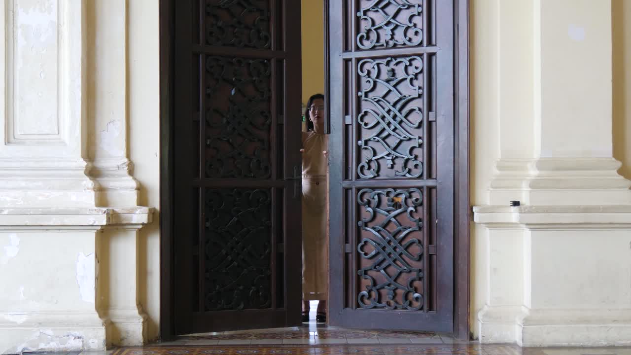 elegante pasillo, puerta de entrada lentamente abriendo, joven mujer asiática emerge