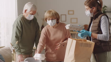 female volunteer unloading groceries for senior couple at home