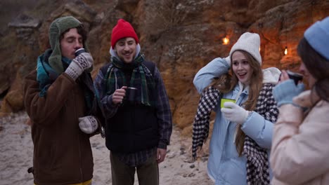 friends enjoying a warm drink on a winter beach