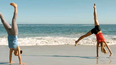 two women doing cartwheels on the beach