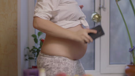 pregnant woman being happy and dancing to cellphone music at home