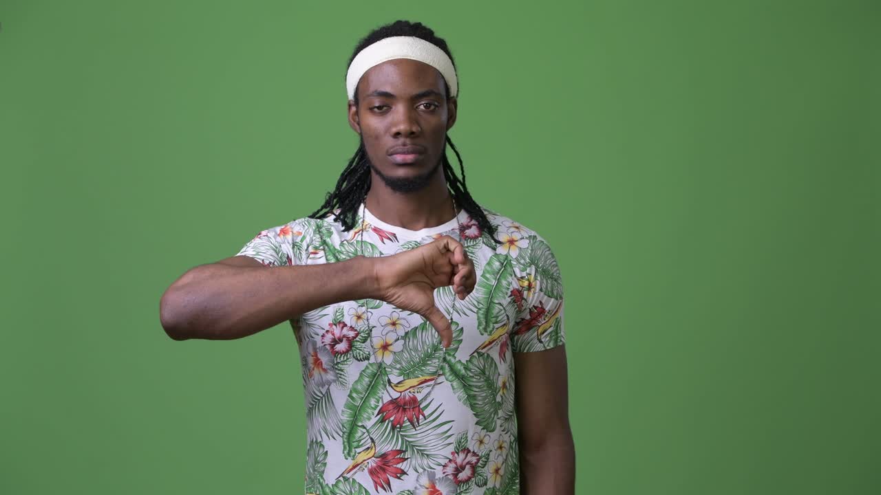 joven hombre africano guapo con dreadlocks contra un fondo verde