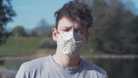 Young-man-puts-on-homemade-white-cotton-corona-virus-mask-MID-SHOT