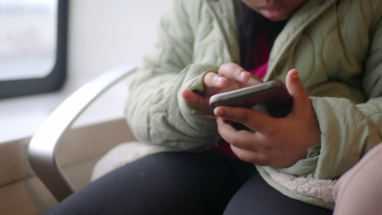 una joven usando un teléfono mientras está sentada en el interior