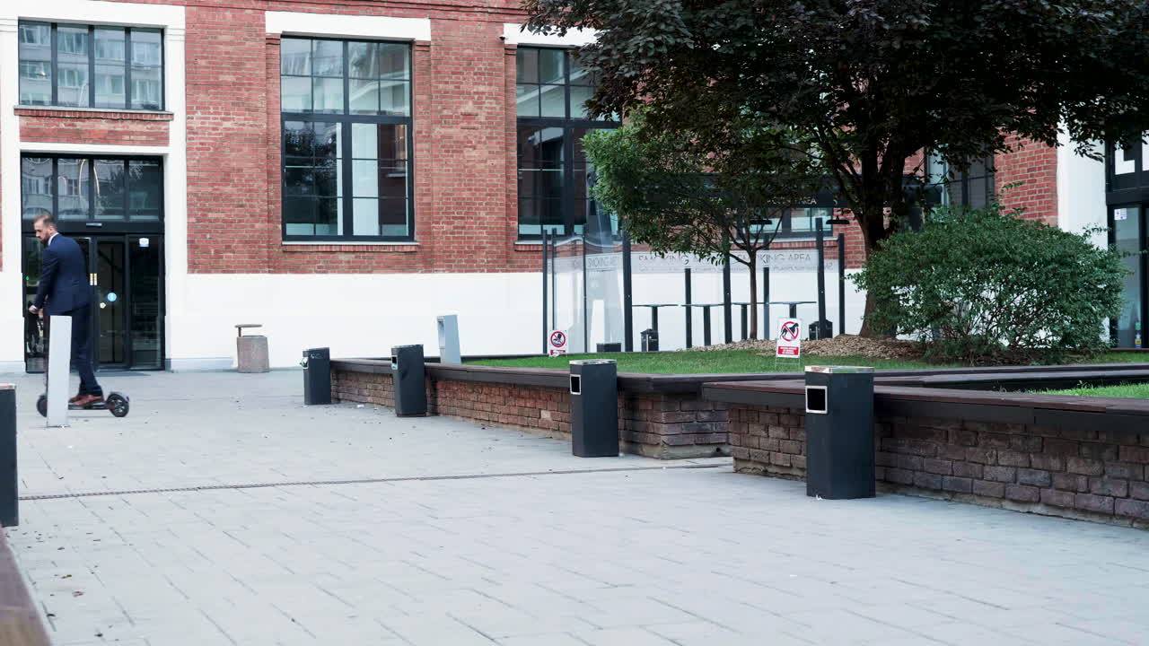 Exterior of a brick building with trees and a man on a scooter