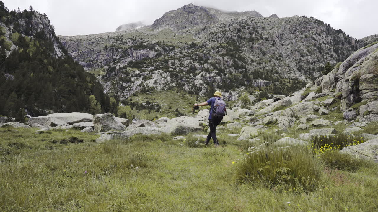 Aig&uuml;estortes National Park Catalan Pyrenees static shot of young adventure trekker walking alone reaching peak of mountains in pure unpolluted natural spot