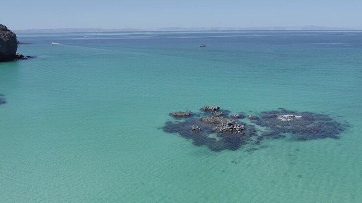 Lateral drone view over rocks in middle of the sea in Balandra Beach