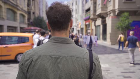 young tourist man walking on busy street.