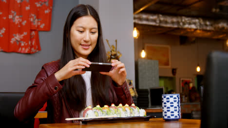 mujer tomando fotos de sushi con teléfono móvil 4k