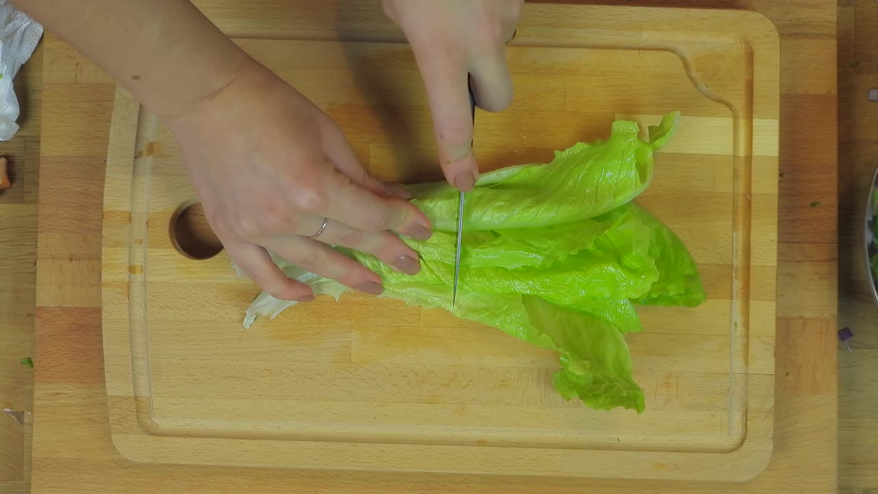 Woman Chopping Lettuce at Wooden Kitchen Table