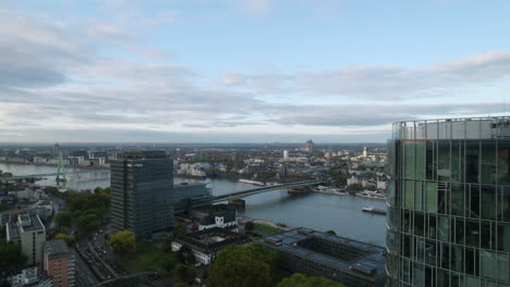 cargo inland vessel sailing over the rhine river in köln while sunlight is reflected in a glass building