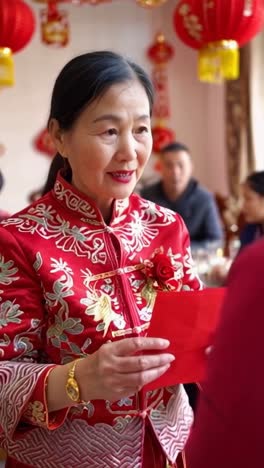 woman holding a traditional red envelope to another person during the chinese new year celebration.