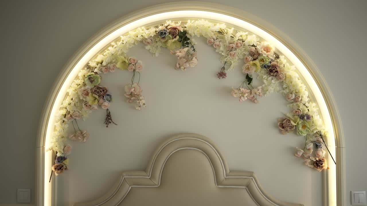 Soft pastel floral arch decor with warm lighting above a cream bed headboard