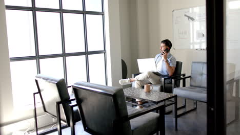 talking on phone and using laptop, man working in modern office space