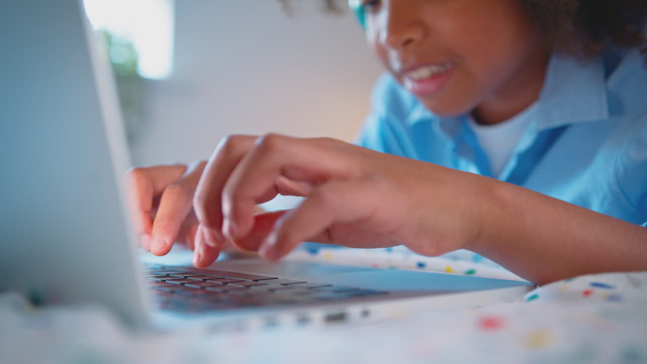 close up de un niño en el dormitorio acostado en la cama usando auriculares inalámbricos usando una computadora portátil