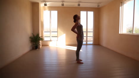 woman performing a stretching or yoga pose in a bright studio