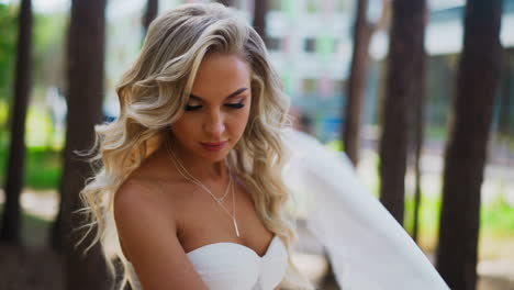 Attractive-lady-bride-in-wedding-dress-stands-in-green-park