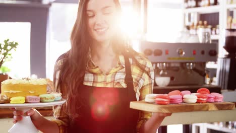 Portrait-of-waitress-standing-at-counter-with-desserts