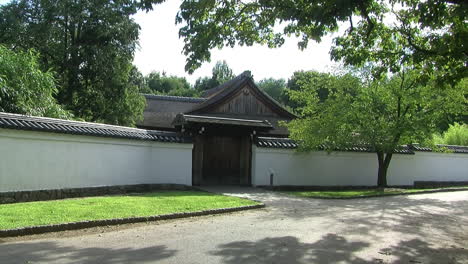 long-shot of the roofed hinoki wood gate and tiled wall at the entrance of a japanese house