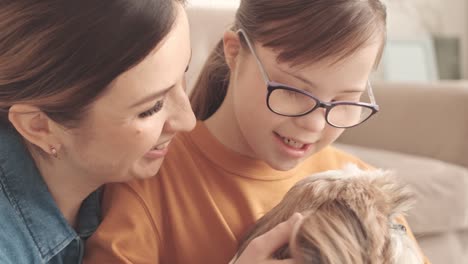 mother and daughter with down syndrome petting dog at home